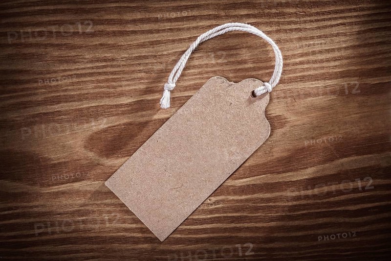 Vintage paper price tag label on old wooden boards close up