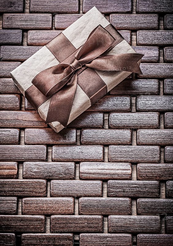 Wrapped present with ribbon on wooden wicker matting holidays concept