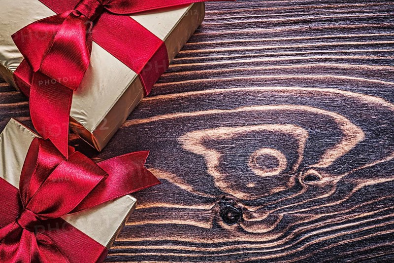 Wrapped gift boxes with red satin ribbons on wood board