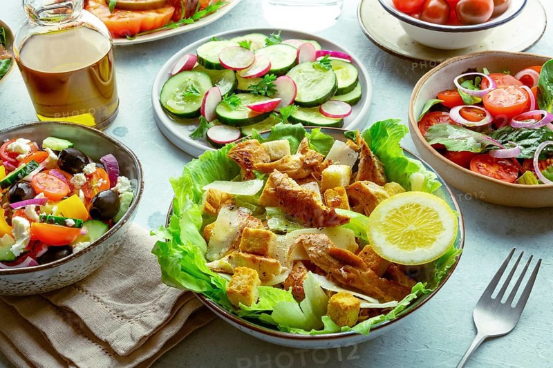 Fresh salads, an assortment. Variety of plates and bowls with green vegetables. Healthy food. Caesar salad with chicken, Greek salad etc, Food photography, Food photography