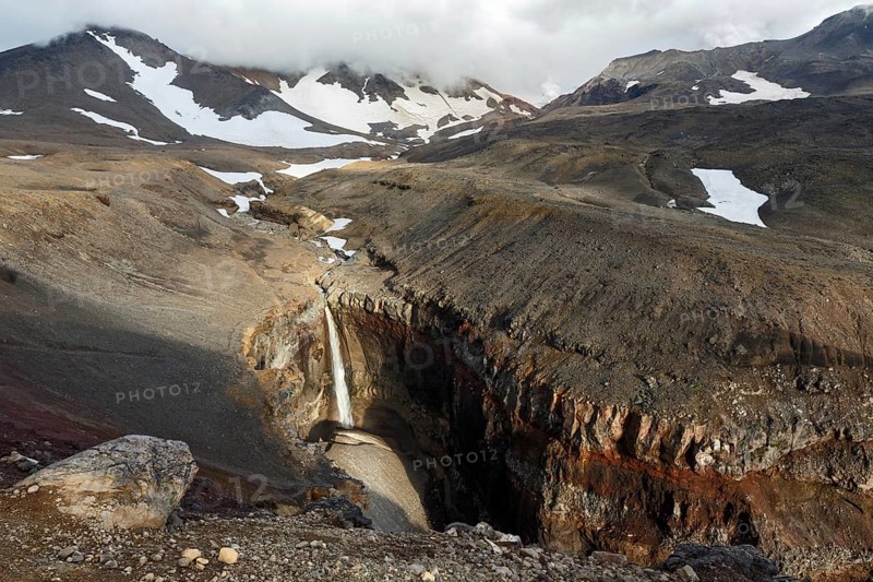Beautiful landscape of Kamchatka Peninsula: view of Dangerous Canyon (Opasny Canyon), picturesque waterfall on the river Vulkannaya under the active Mutnovsky Volcano. Kamchatka, Far East, Russia, Europe