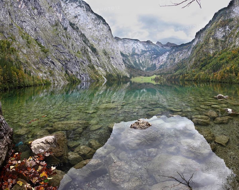 Magic reflection in German lake Koenigssee. Cloudy day on the lake. Clouds and mountains reflected in the mirrored surface of the water