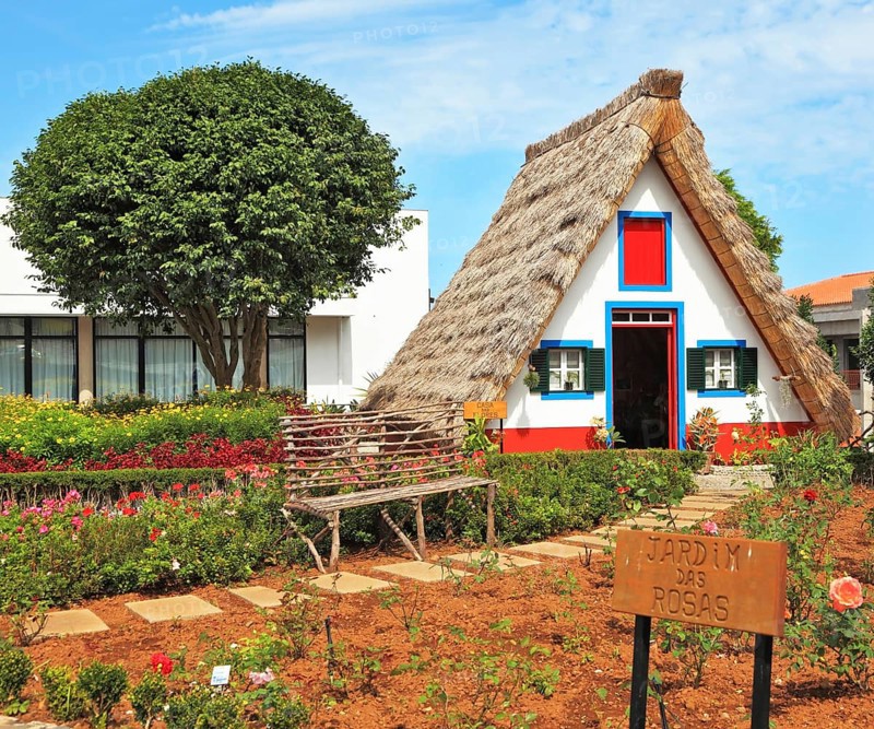 Old house-museum of the first settlers on the island of Madeira. Charming white cottage with a thatched roof and gable small garden with flowers