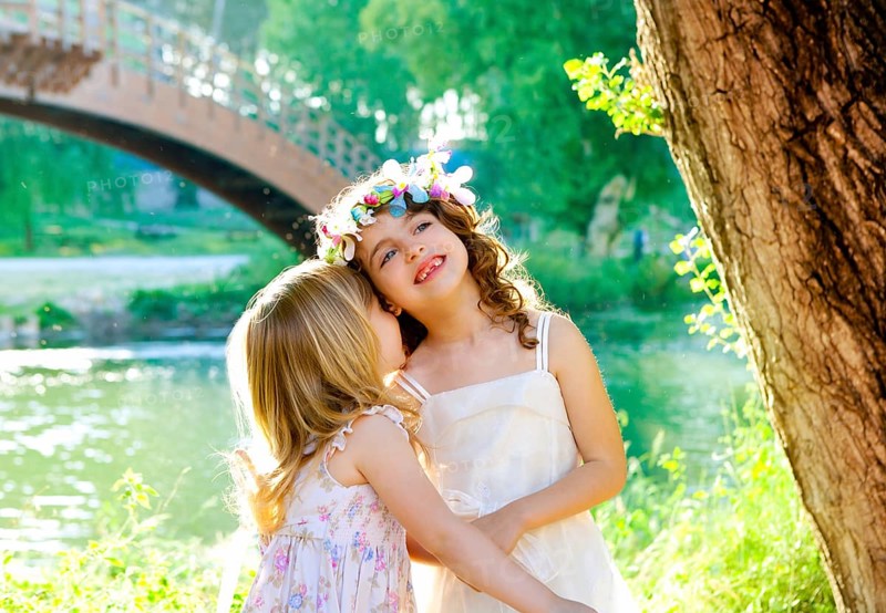 Kid girls playing in spring outdoor river park whispering ear