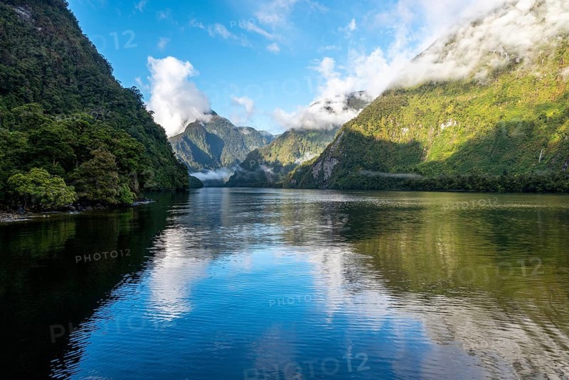 A new morning dawning at Doutful Sound, clouds hanging low in the mountains, South Island of New Zealand