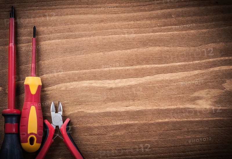 Sharp nippers insulated screwdrivers on wooden board copyspace electricity concept