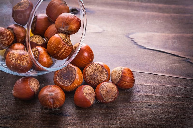 Hazelnuts and glass on vintage wooden board food and drink concept