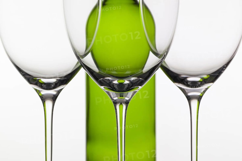 Three empty glasses of wine and green bottle on the white background