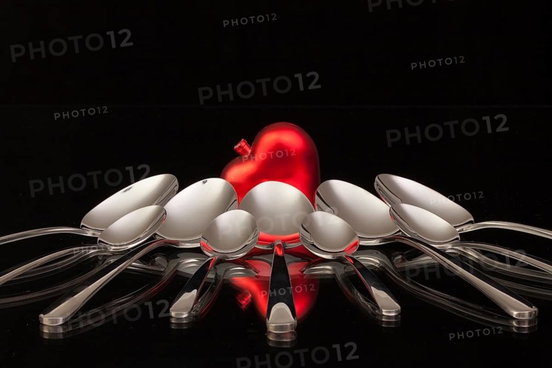 Nine spoons and red heart on a black glass desk