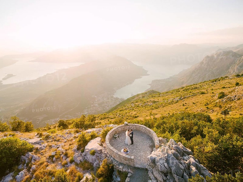 Bride and groom standing on the observation deck on the mountain against the backdrop of the Bay of Kotor.
