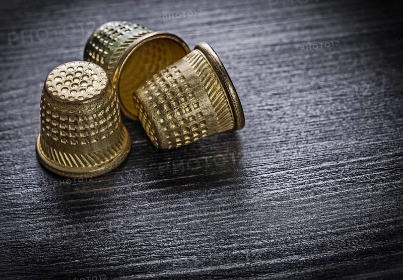 Metal thimbles on wooden board fancy-work concept