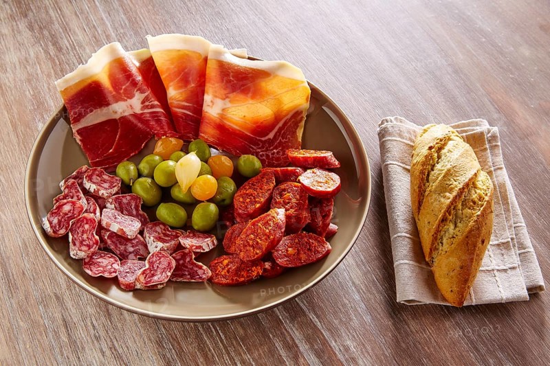 Tapas of Spain with ham bread olives sausage and chorizo on wooden background