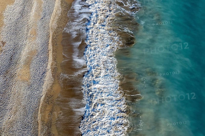 Aerial view of stormy ocean waves breaking on a sandy beach. Nature background
