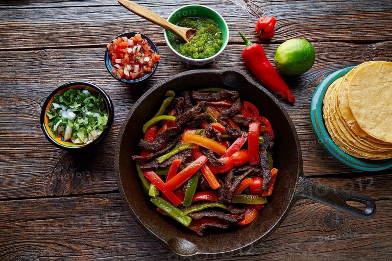 Beef fajitas in a pan with sauces chili and sides Mexican food