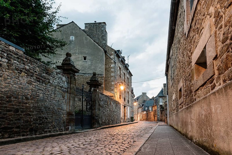 Old cobblestoned street with stone medieval houses in the town centre of Dinan, French Brittany