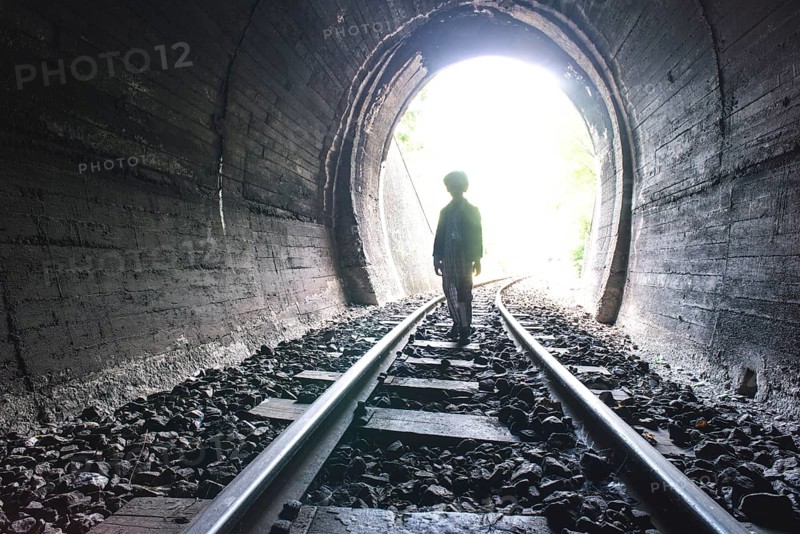 Child walking in railway tunnel. Vintage clothes