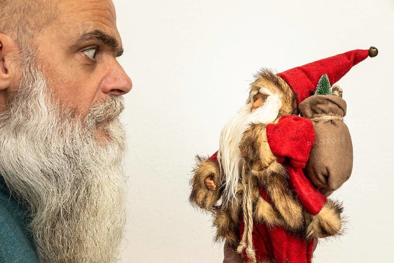 An image of a bearded man looking to a Santa Claus puppet