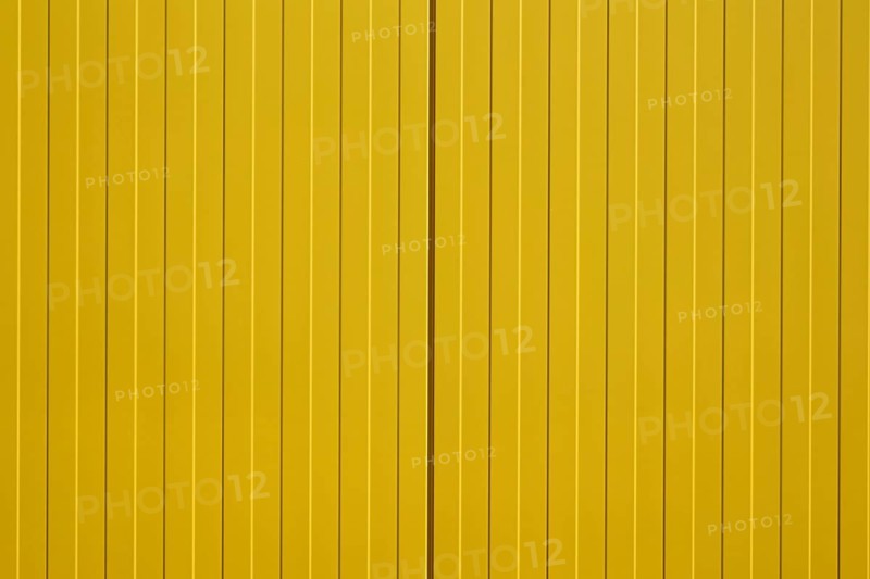 The close-up of a colourful and bright yellow corrugated metal wall of a shopping centre