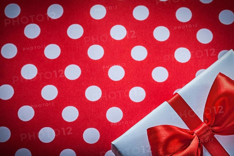 White present box with knot on polka-dot red fabric holidays concept