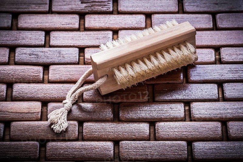 Wood peeling brush on textured wooden matting close up view healthcare concept