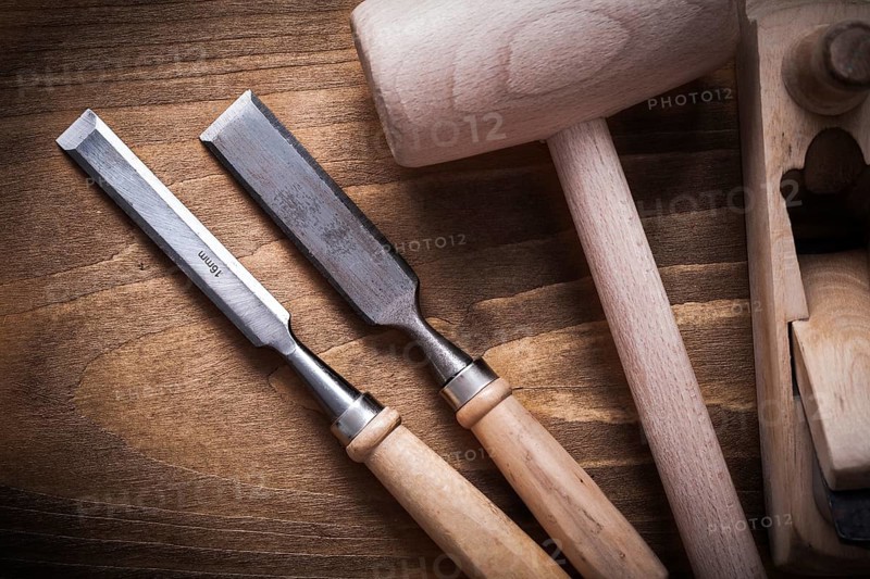 Wooden hammer shaving plane flat chisels on wood board top view construction concept