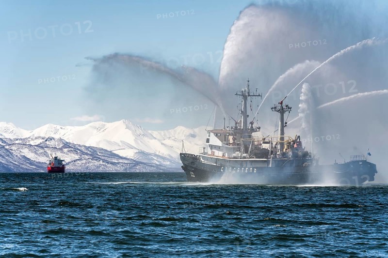 KAMCHATKA, RUSSIA, APR 27, 2019: Firefighting and rescue ship of Pacific Fleet of Russia spraying water on ocean for supporting emergency case of fire of warships, cargo ships, oil and gas industry
