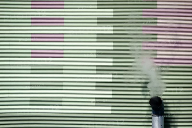 The smoking chimney of an industrial plant on the outer wall of a power station