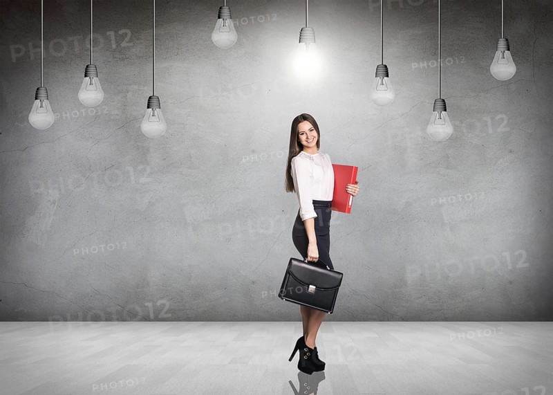 Business woman stnads in a gray room with hanging bulbs