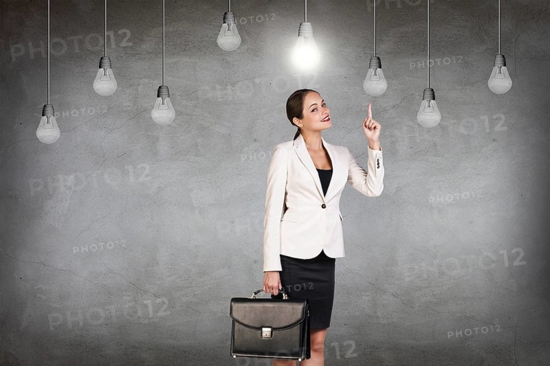 Business woman stands in a gray room with hanging bulbs