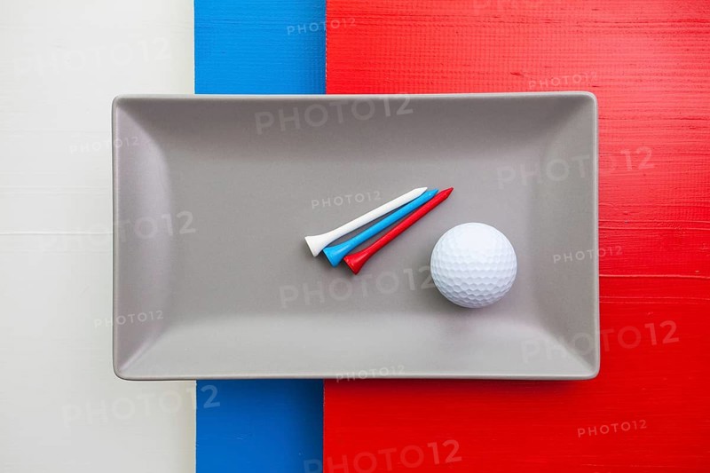 Gray ceramic dish with golf equipments on over white, blue and red wooden table, rectangle dish