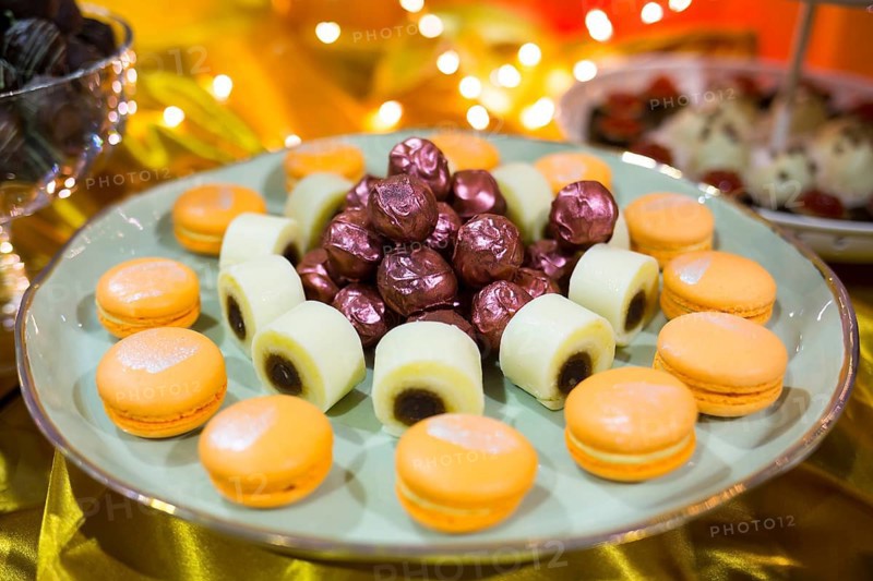 Circular cake macaron or macaroon is a sweet meringue-based confection. Extremely tasty and delicious desserts. Sweets full with sugar. Unhealthy food diet. In a plate with purple wrapped bonbons