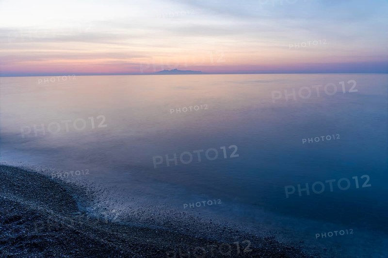 Dawn, cloudy mood in front of sunrise, view from the lava beach to the island of Anafi, long exposure, Kamari, island of Santorini, Cyclades, Greece, Europe