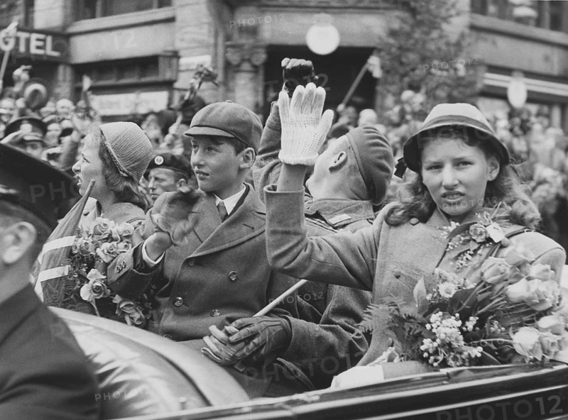 Norwegian royal family. Pictured here 1945 when returning to Norway and Oslo when world war ii was over. Crown Prince Harald, his sisters Ragnhild and Astrid and Crown Prince Olav in a car waving at the cheering crowds in a Oslo street. June 7 1945