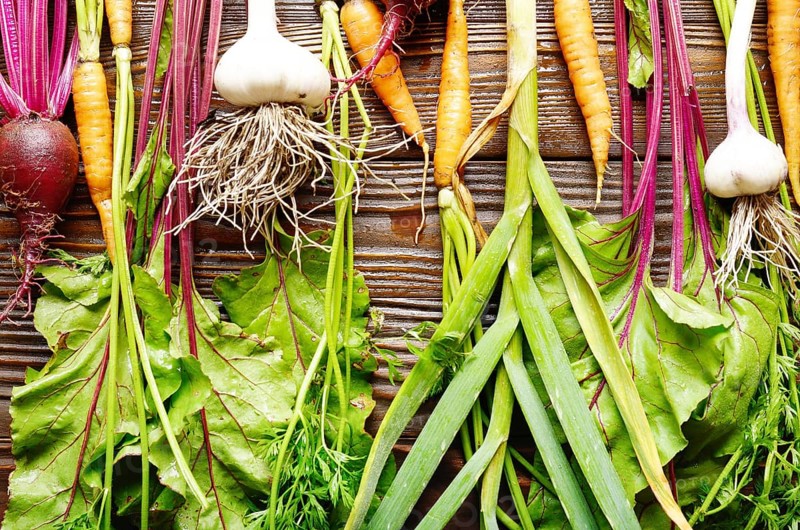 Vegetarian background of fresh organic beetroots green garlic and carrots on kitchen wooden rustic table