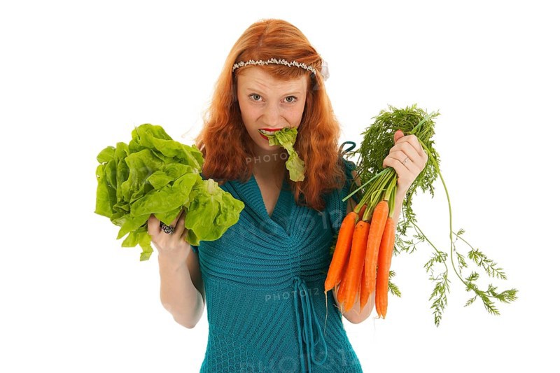 Young woman eating lettuce and carrots for diet isolated over white background