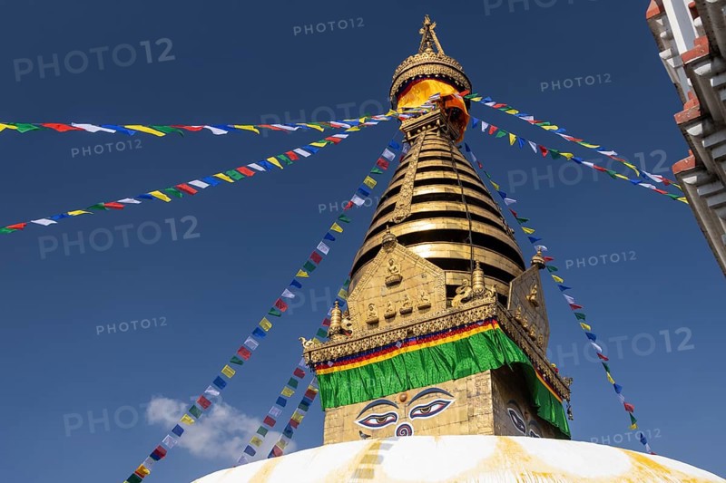 Swayambhunath, Swayambhu Mahachaitya, sometimes called the Monkey Temple, the Swayambhu stupa, one of the UNESCO World Heritage Sites of the Kathmandu Valley photographed in winter against the blue sky. On the white dome, with a pigeon walking on it, stands a cubic part, the harmika, with eyes painted on its four sides, known as Eyes of Buddha or Wisdom Eyes. The golden spire is above it, and Buddhist prayer flags hang from the top. Kathmandu Metropolitan City, Bagmati Province, Nepal, Asia