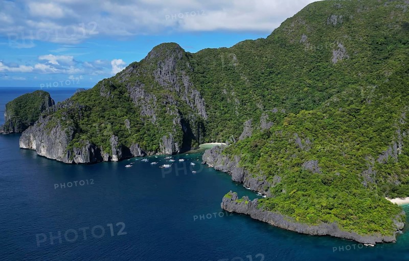 Aerial view of tropical Philippines island. White sand beach, rocks cliffs mountains with blue bay and coral reef