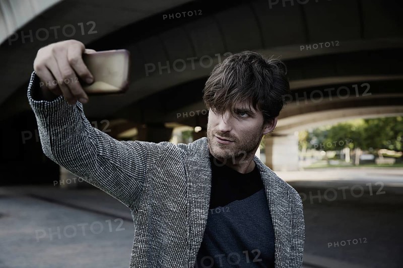 Modern young man smartphone taking selfie photos under a bridge