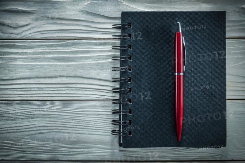 Black notepad pen on a white wooden board