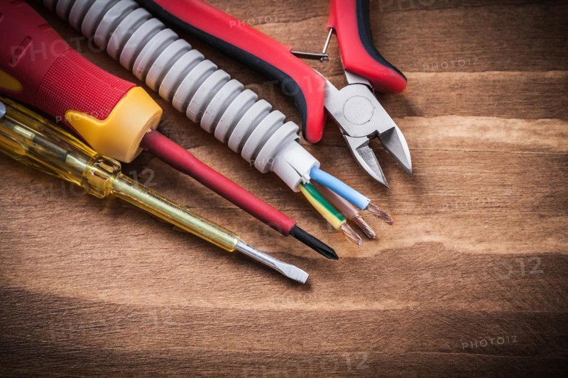 Nippers insulated screwdrivers corrugated pipe on wooden board
