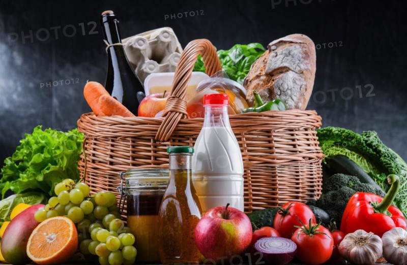 Wicker basket with assorted grocery products including fresh vegetables and fruits