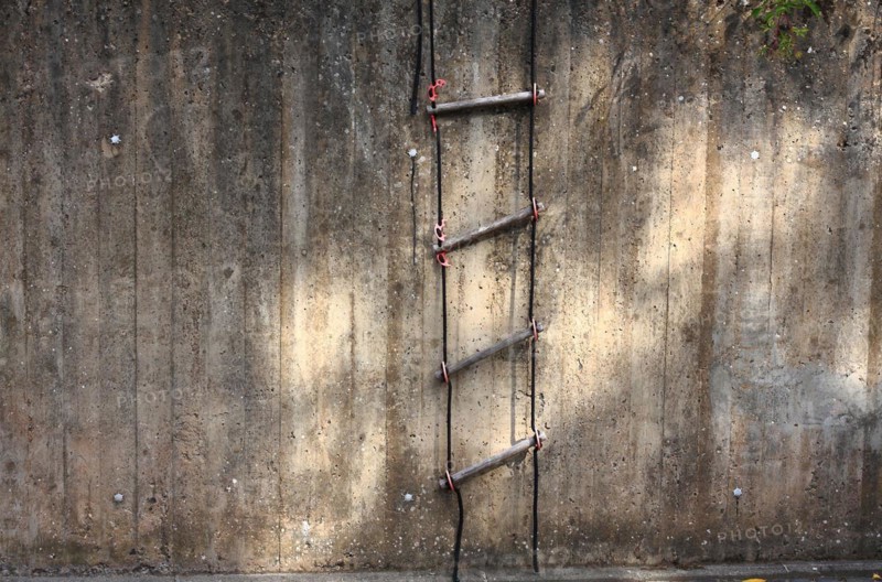 Rope ladder on a concrete wall with sunlight reflections