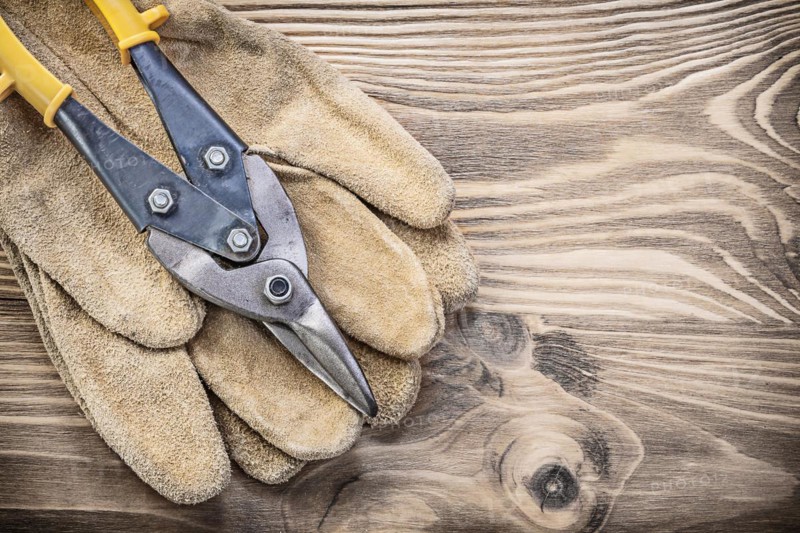 Pair of safety gloves steel cutter on vintage wooden board construction concept