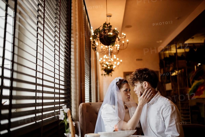 An intimate moment between a bride and groom inside a warmly lit room with chandeliers