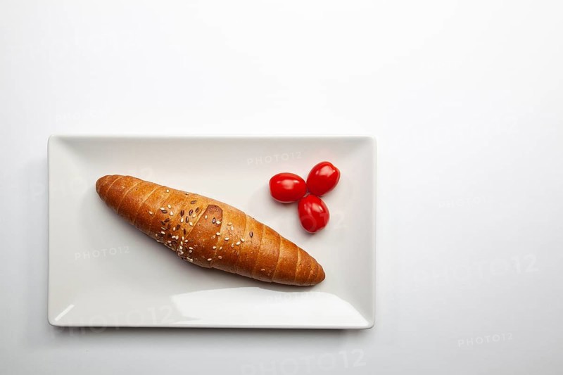 Diet breakfast. French baguette and red cherry tomatoes on the white table