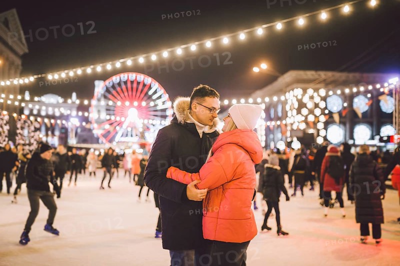 Couple hugging in Saint Valentine's Day. Young romantic couple having fun outdoors in winter. St Valentines Day at city ice rink. New Year holidays. active date ice skating on ice arena on Christmas