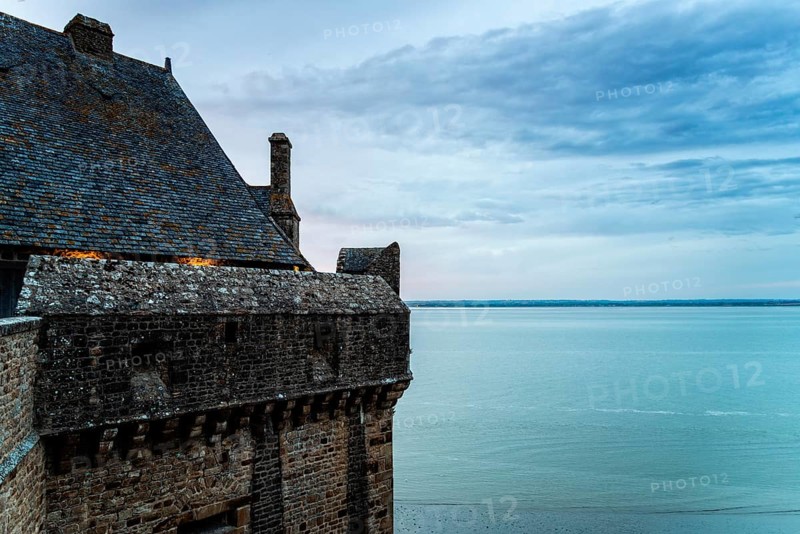 View of the ramparts of Mont Saint Michel with the tide coming in at sunset. Normandy, France, Europe