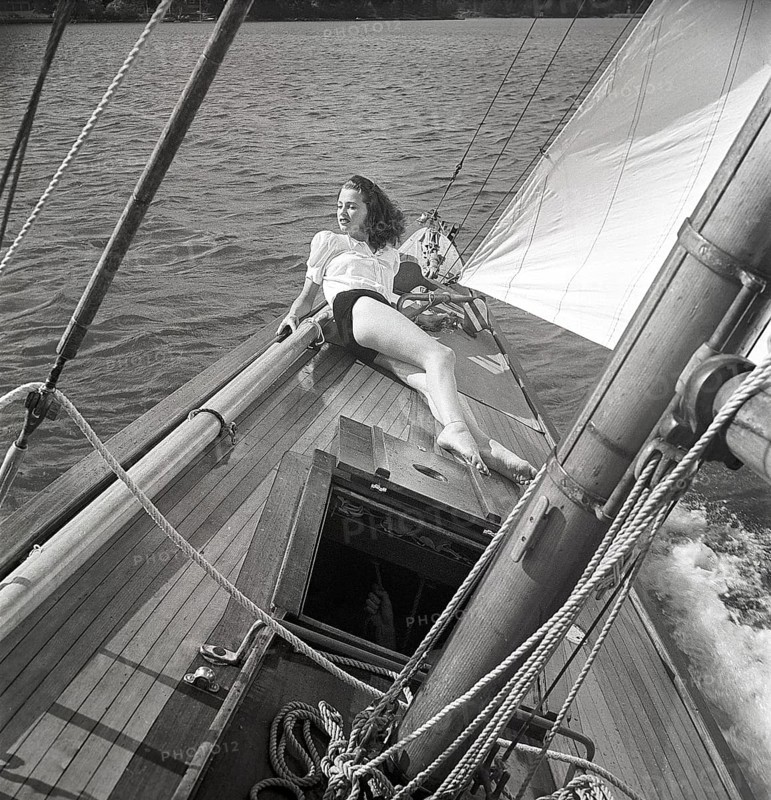 1940s sailing boat. A young woman is aboard a fashionable sailing boat and is lying on deck when it cruises forward with wind in the sails. She is wearing a typical 1940s fashion. Sweden 1946 Photo Kristoffersson ref AC102-2
