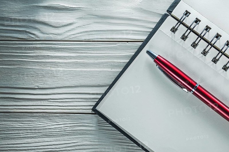 Opened notepad pen on white wooden board