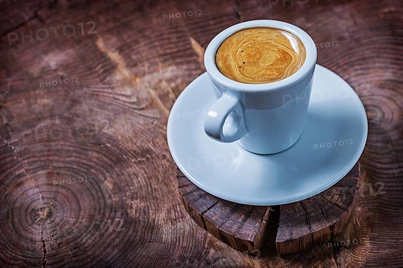 White coffee cup with capuchino on vintage wood cross cutted tree trunk
